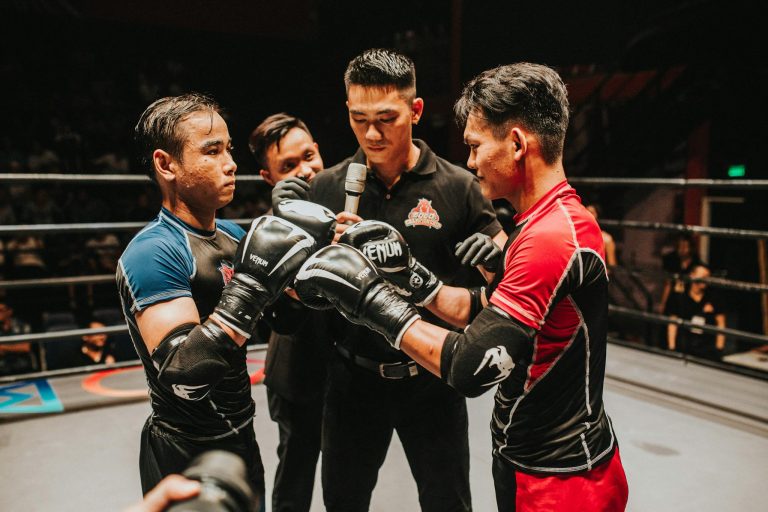 Two boxers and a referee engage in an intense pre-fight moment in the boxing ring.