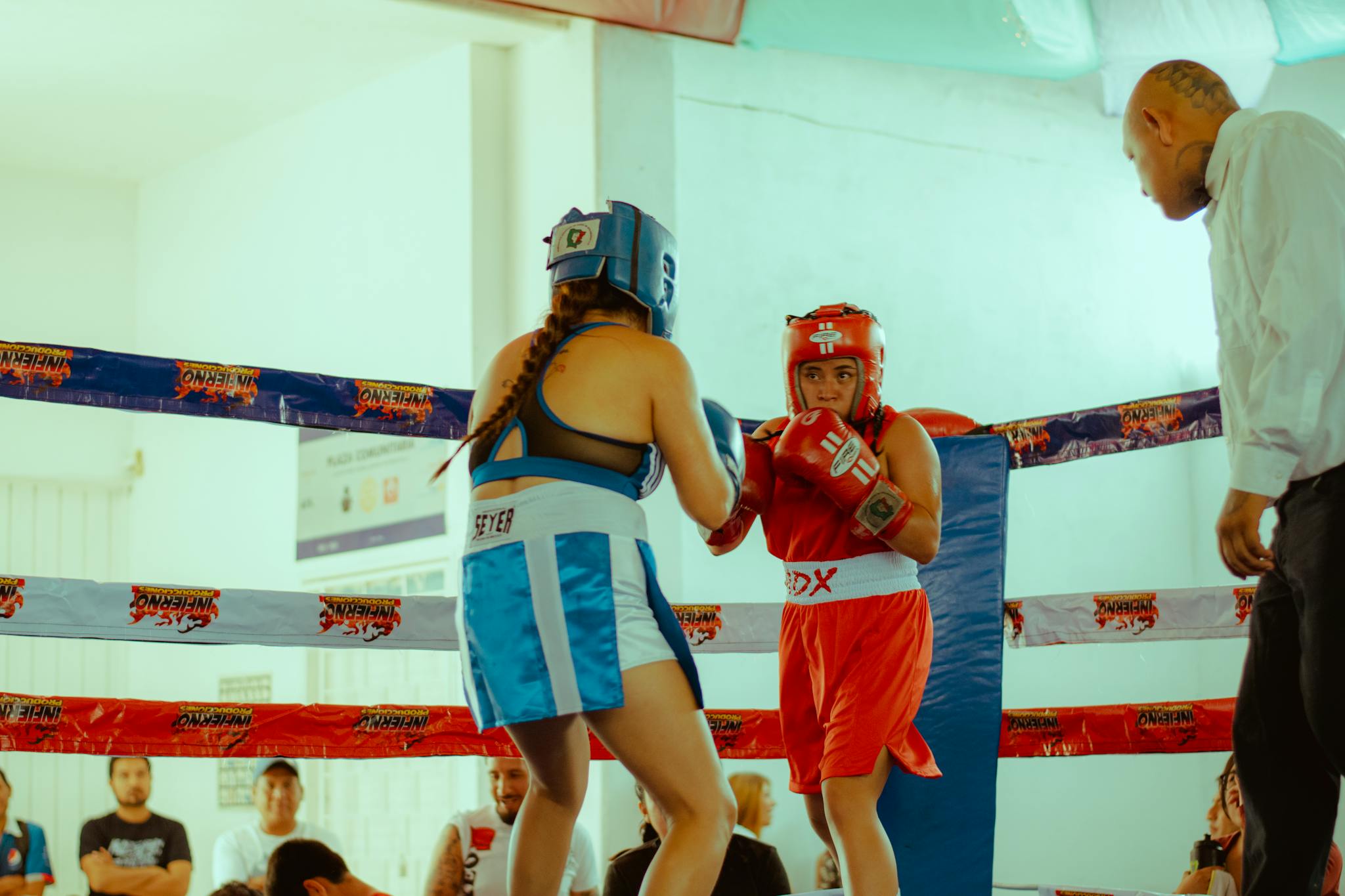 Two female boxers compete in a lively amateur match, showcasing skill and determination.